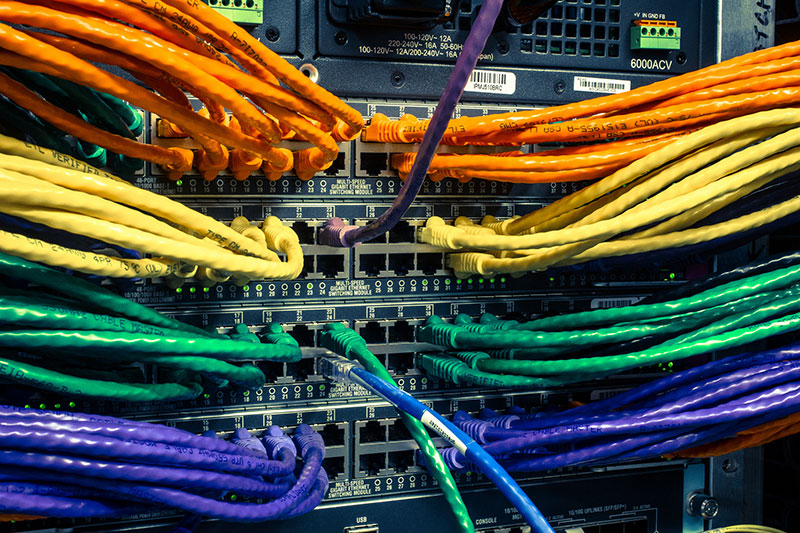 picture of a server rack with multi-color cat6 cords plugged in